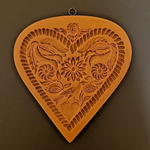 Decorative heart-shaped wall hanging with floral and leaf patterns on a brown background