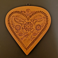 Decorative heart-shaped wall hanging with floral and leaf patterns on a brown background